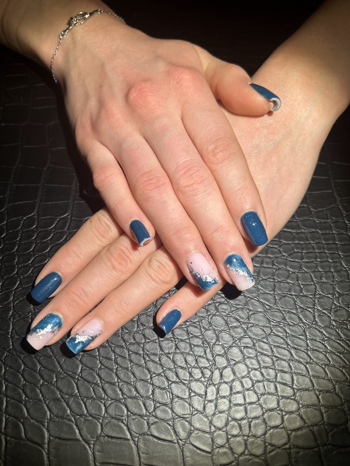 Blauwe nagels met wit en blauw marmereffect op een donkere ondergrond