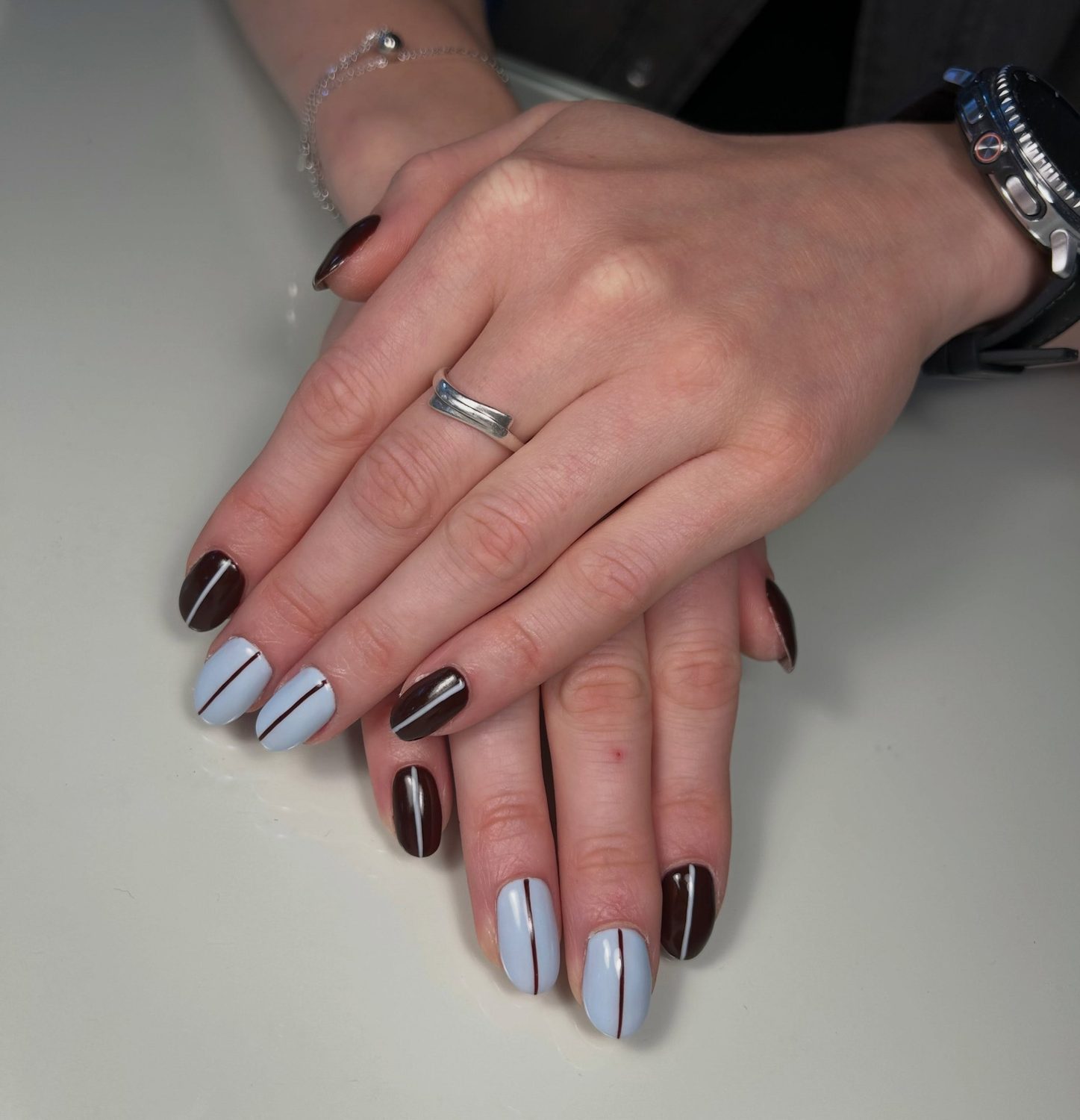 IJsblauwe nagels met een donkerbruine streep naast donkerbruine nagels